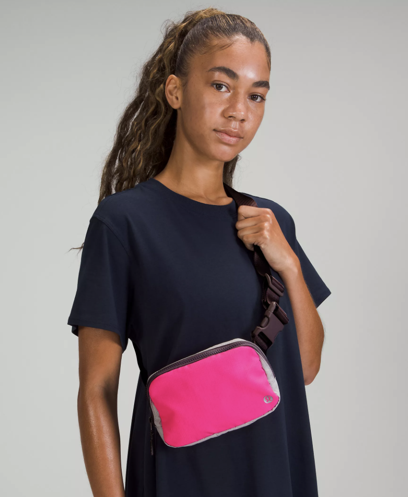 a model wearing a crossbody belt bag in hot pink