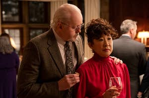 Photo of Sandra Oh in the chair with a white male colleague putting his hand on her shoulder