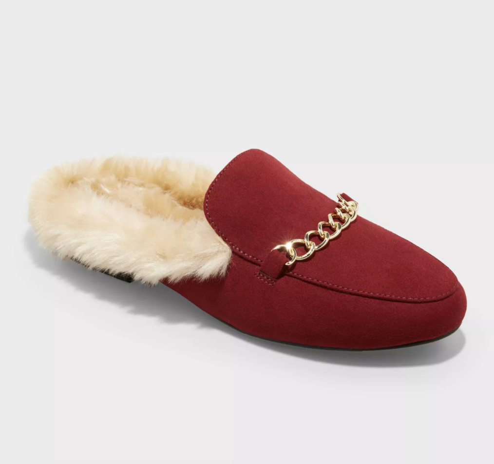 a red slip on shoe with faux fur lining and a gold chain across the middle