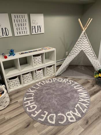 Reviewer's photo showing the gray and white alphabet round rug in their kid's room