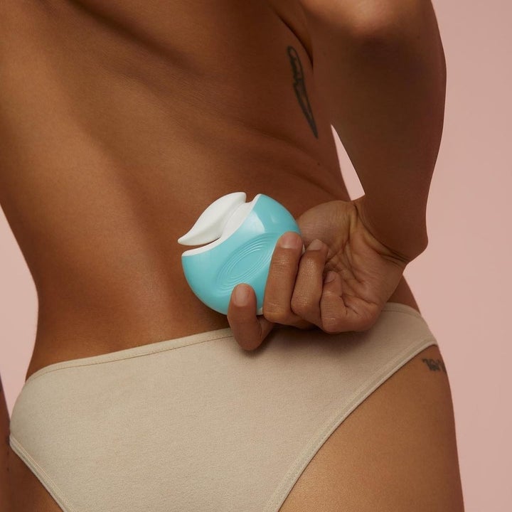 Model holding blue and white vibrator behind back