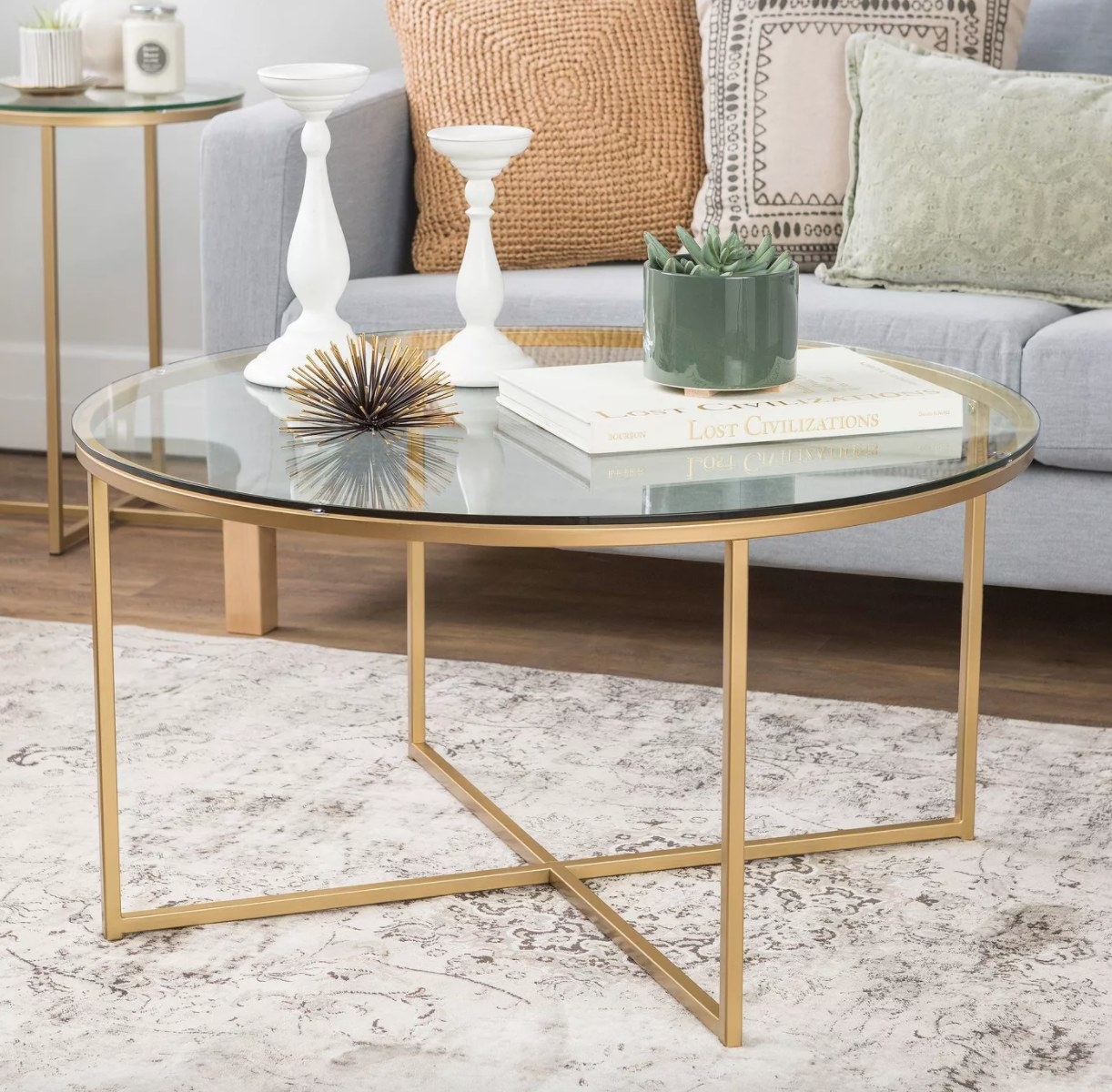 A round coffee table with metallic legs and glass top