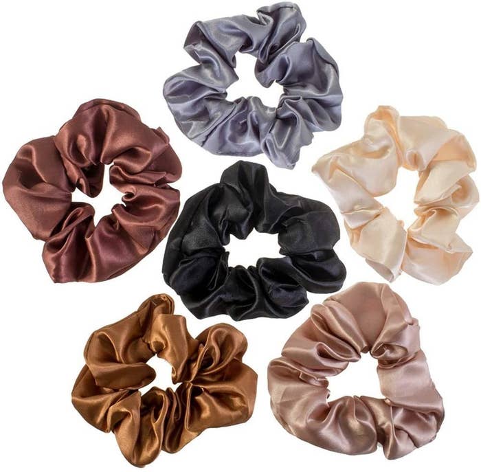 Six satin scrunchies that are black, cream, silver, champagne, gold and maroon coloured.