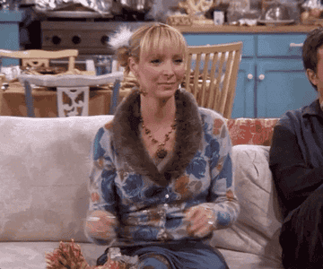 Lisa Kudrow as Phoebe Buffay from Friends sits on a couch saying &#x27;wow&#x27; in an astonished manner