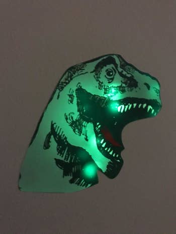 Reviewer's photo of a dino decal glowing on the wall