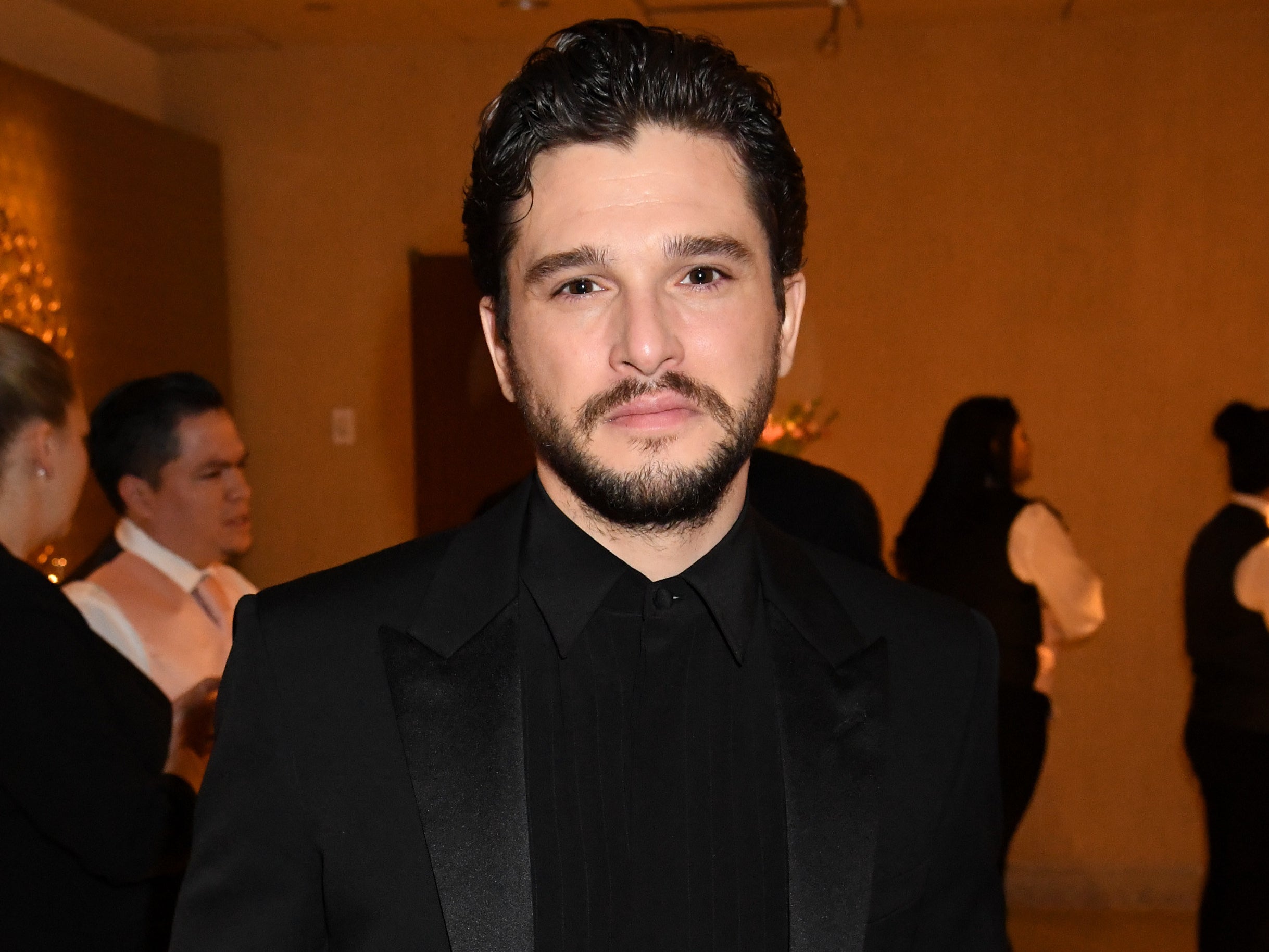 Kit wears a black suit jacket and black shirt at an event