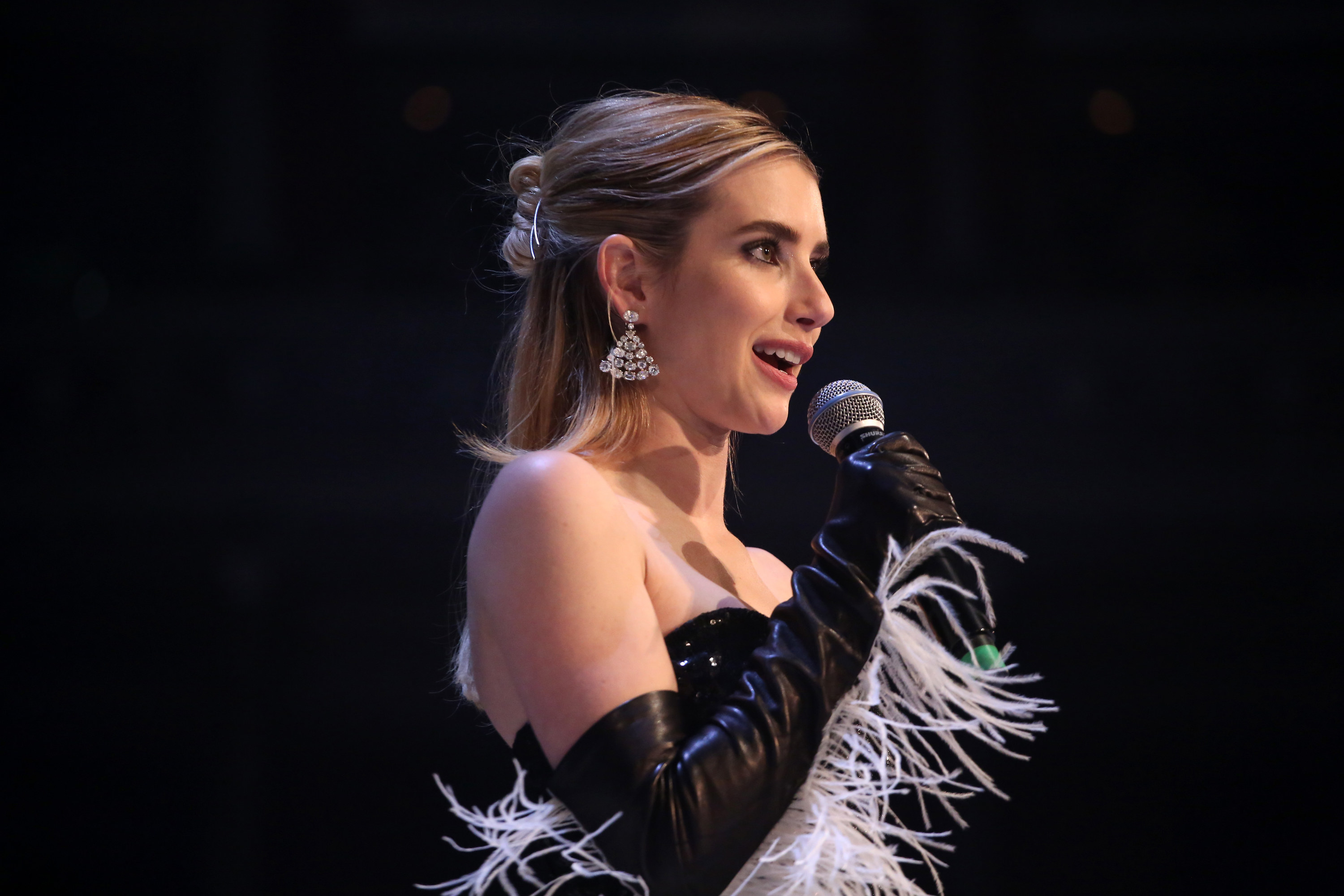 Emma Roberts speaks into a microphone onstage