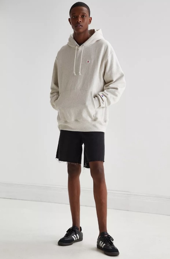 Model wearing light gray hoodie with black shorts and sneakers