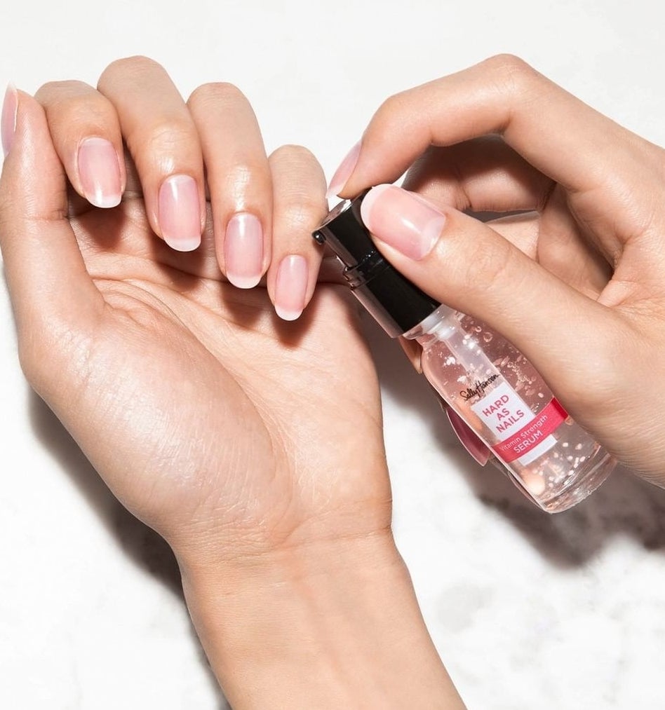 A person holding the bottle up to their nails