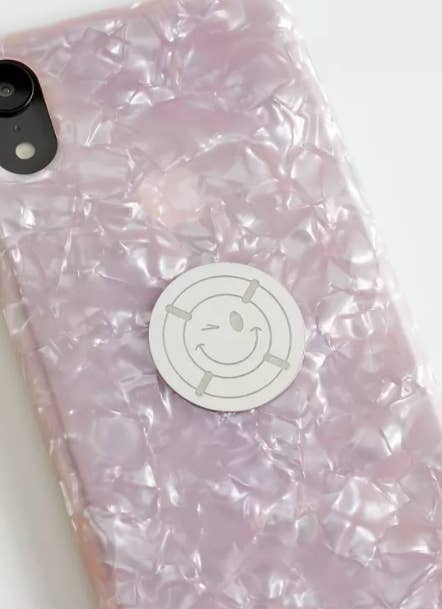 A close up of a radiation-blocking sticker on a phone case; it has a smiley face design