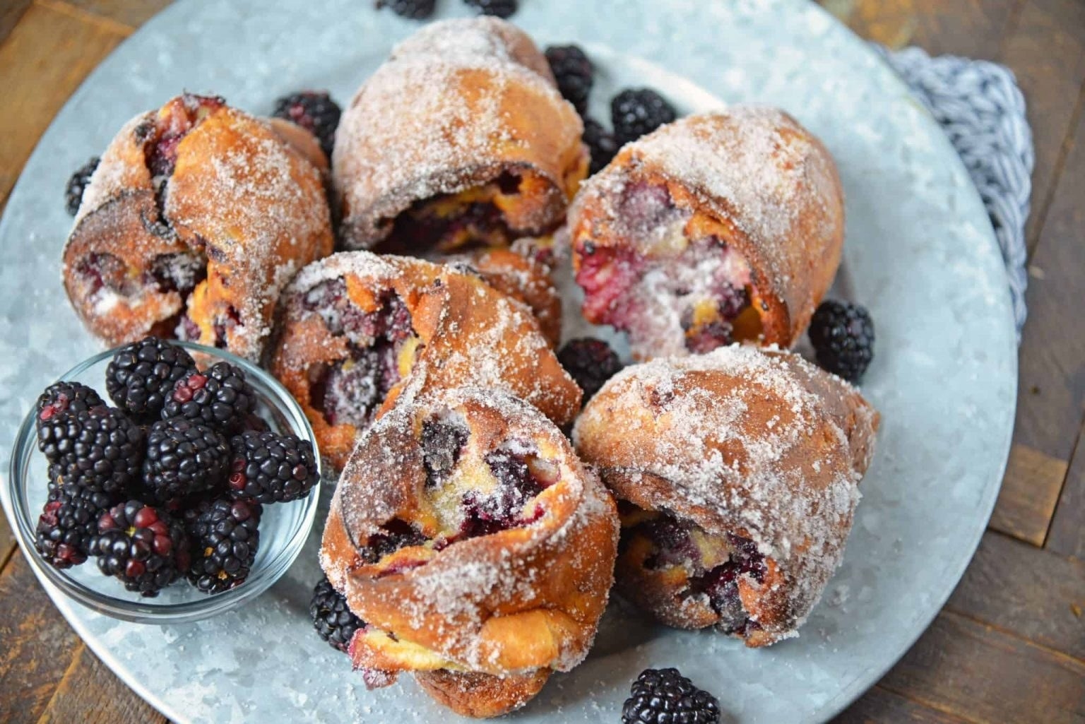 A plate of blackberry popovers with powdered sugar.