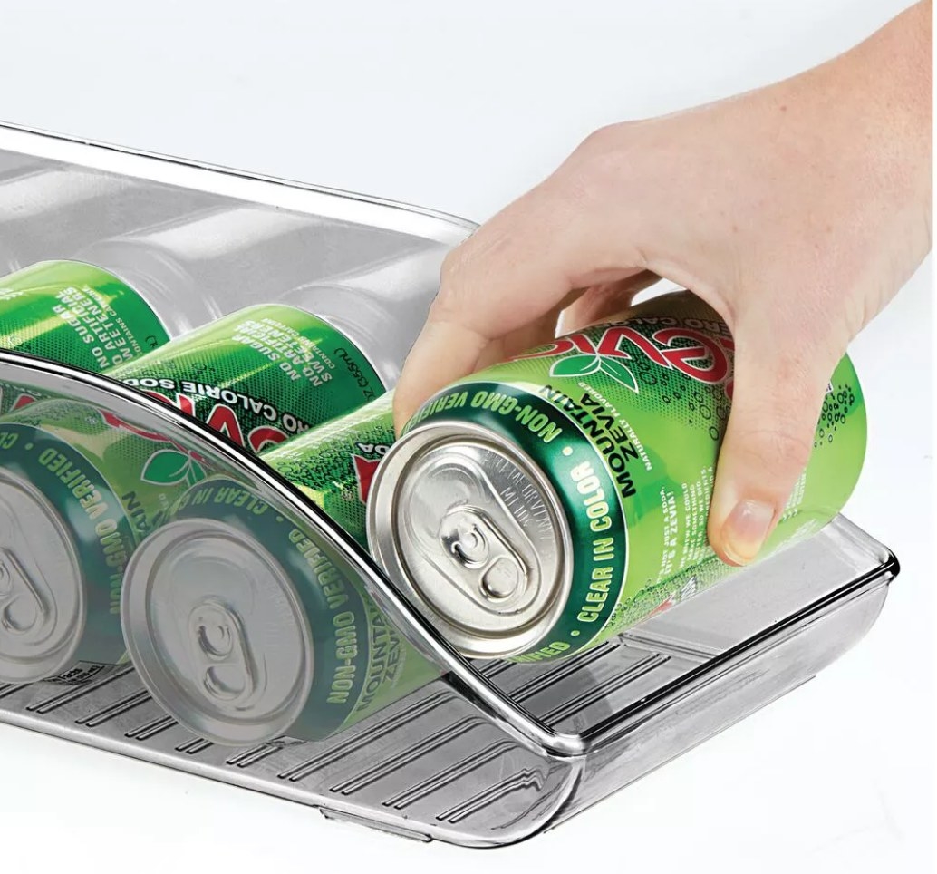 A model grabbing a soda from a can storage dispenser made for the fridge