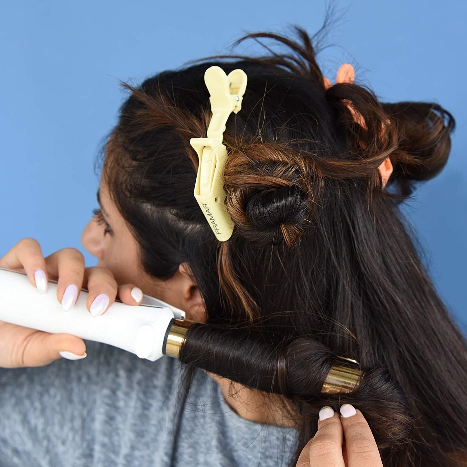 A person with the clips in their hair while styling it with a curling iron