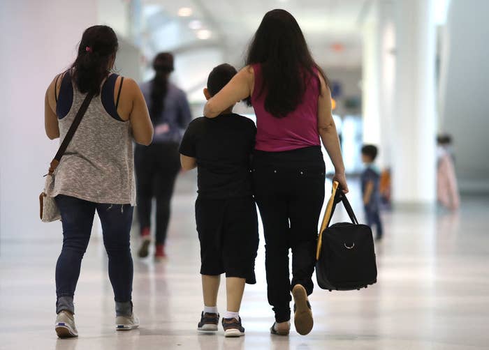 A mother walks beside her child with an arm around them