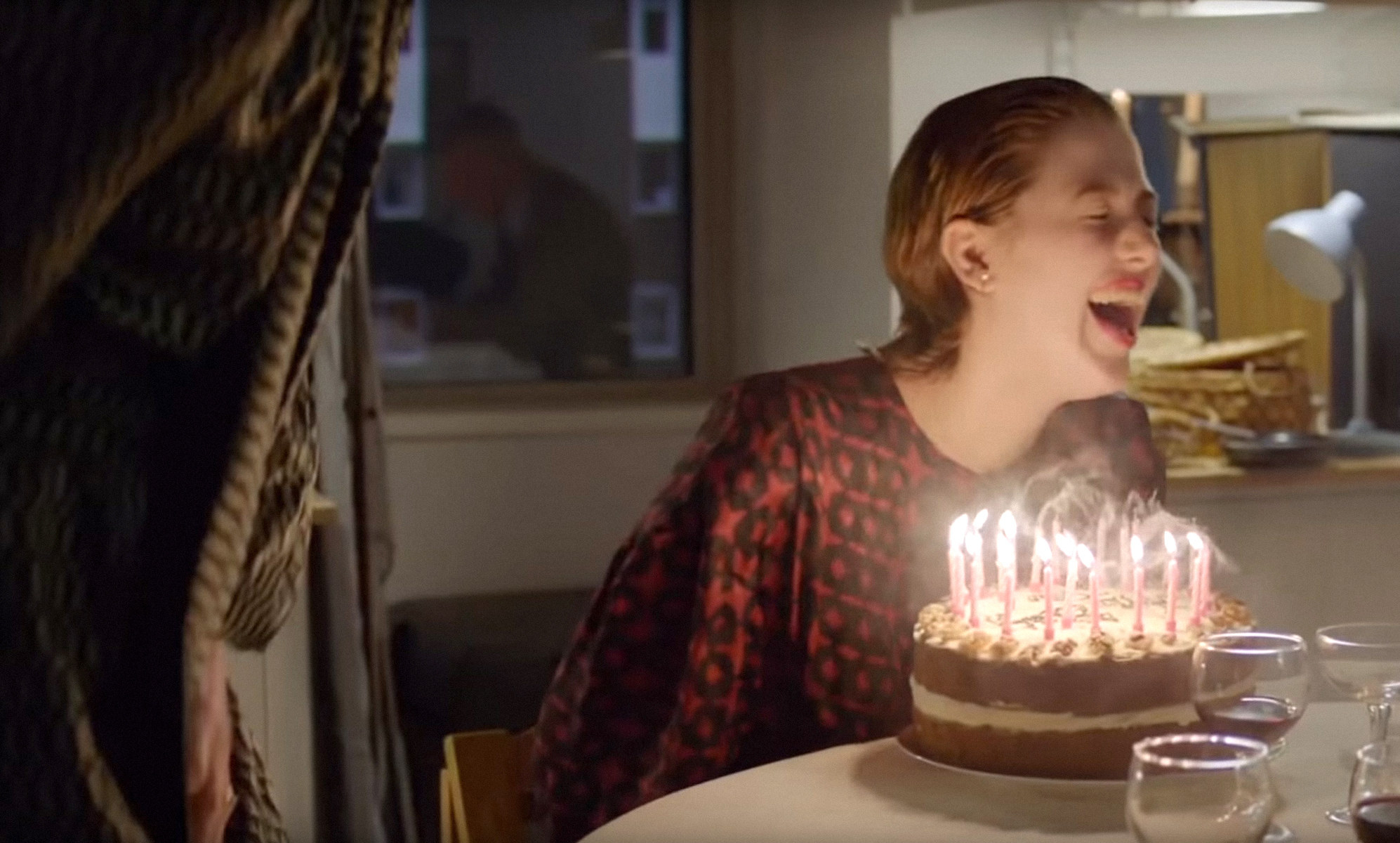 Honor Swinton Byrne laughs with a birthday cake in front of her