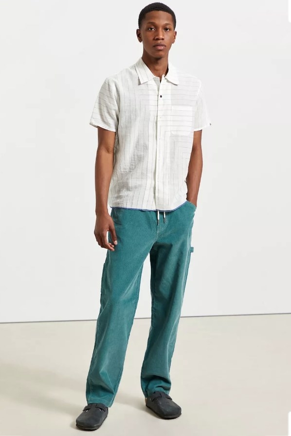 Model wearing green corduroys with white button down