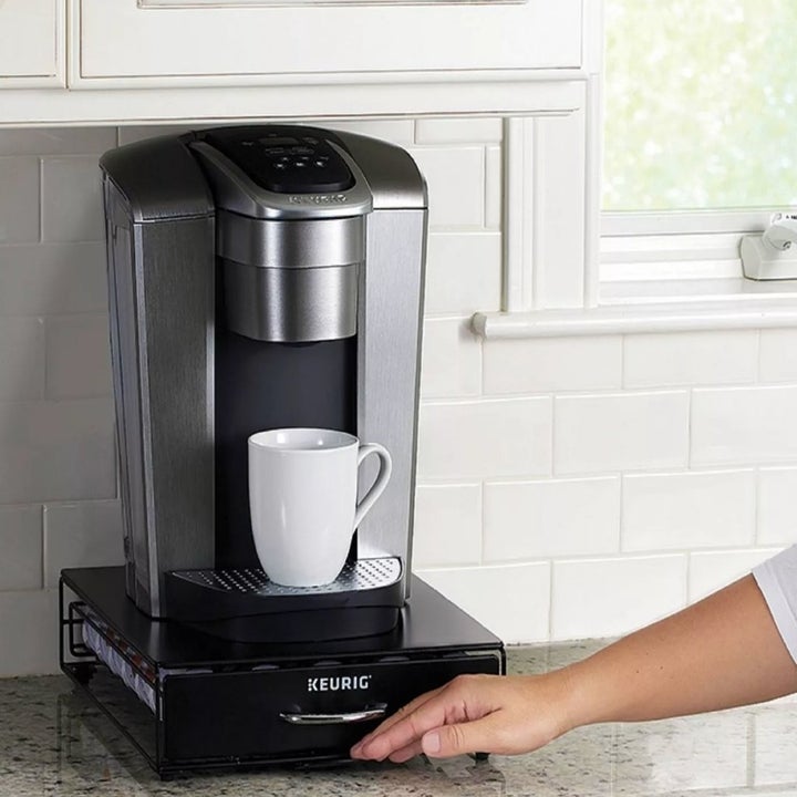 A model pulling out a K-cup storage drawer under a Keurig coffee maker