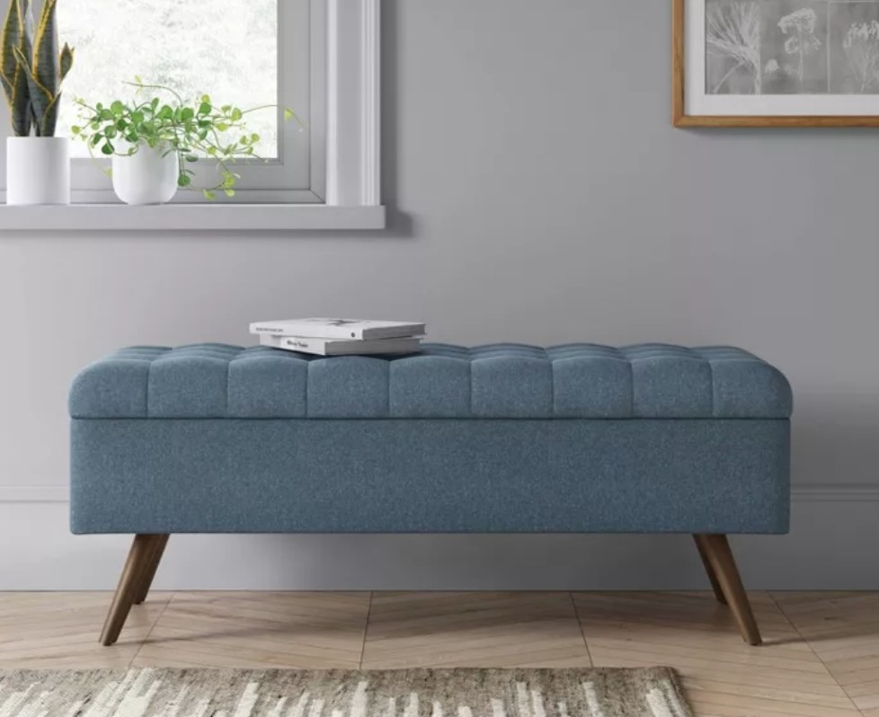 A blue, tufted storage ottoman in an entryway