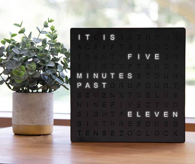 the word clock next to potted plant reading 