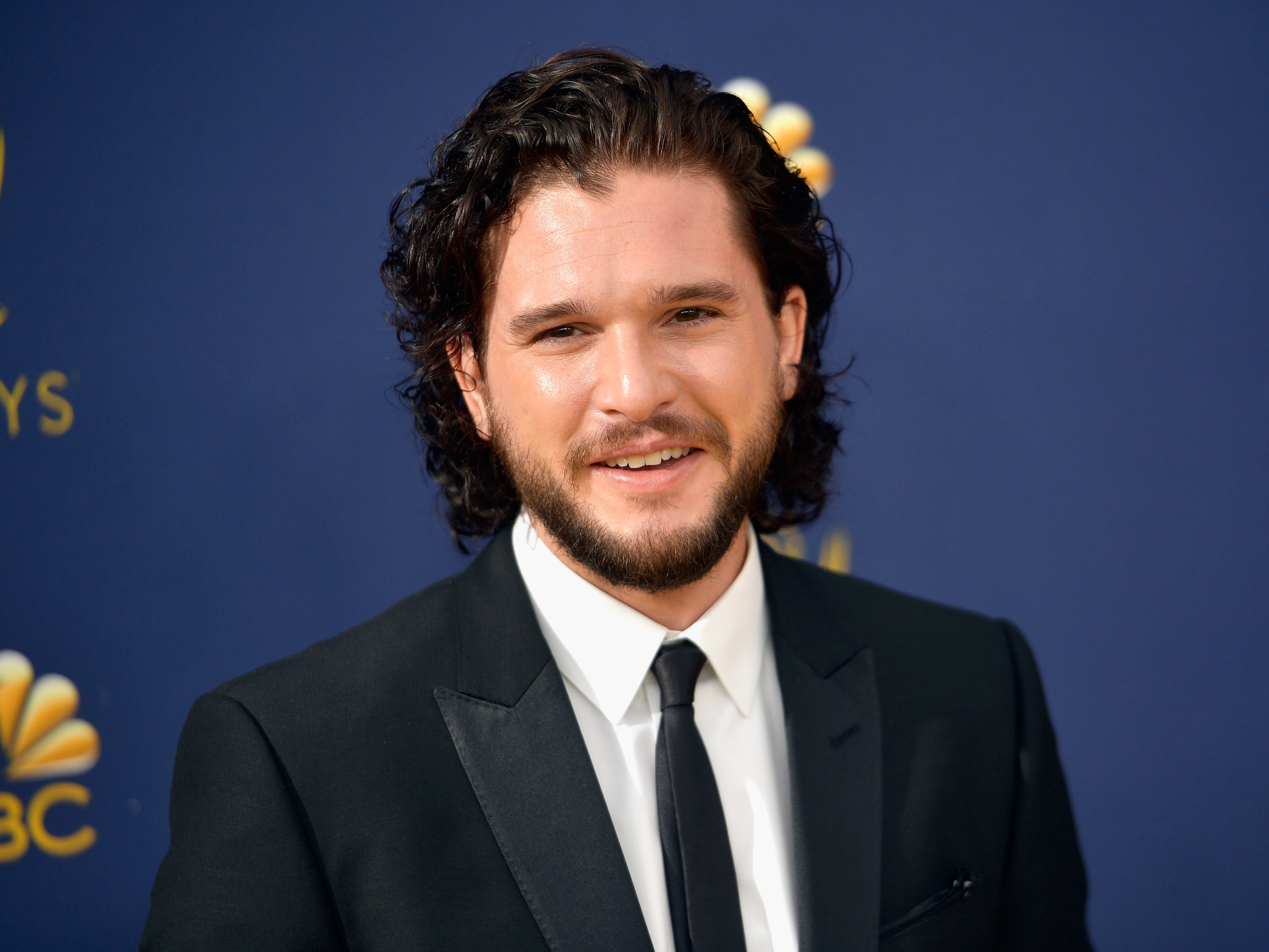Kit wears a black suit and black tie at an event