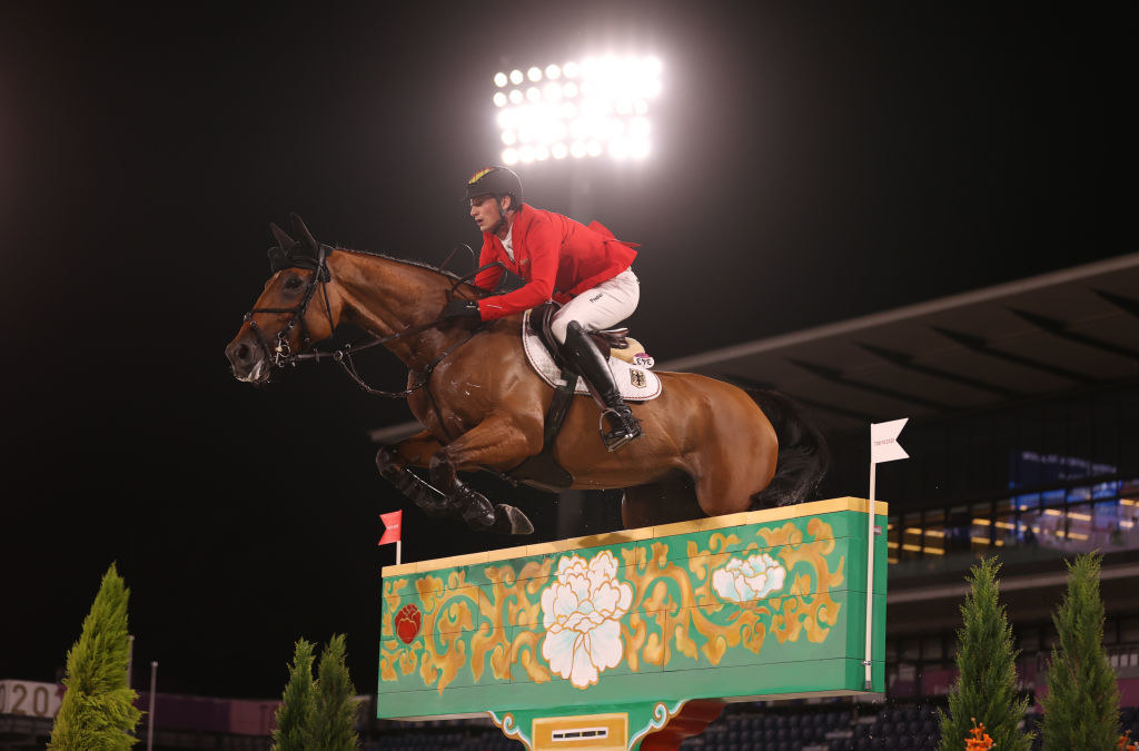Olympic equestrian on a horse jumping over an obstacle