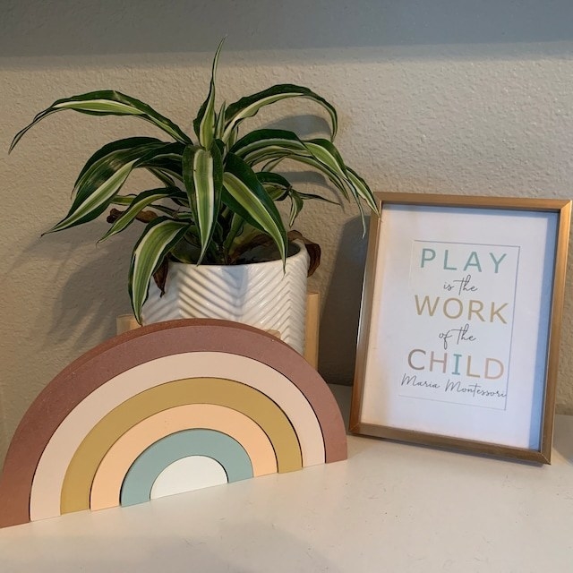 Reviewer's photo showing the wooden rainbow stacker in custom colors displayed next to a poster and a plant