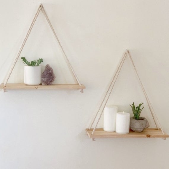 The rope shelves hanging on a wall and displaying plants, candles and a crystal rock