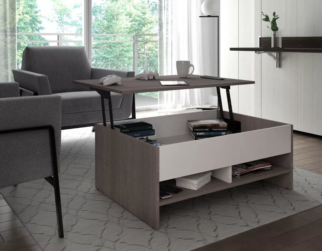 A gray/white coffee table with a lift top for storage and 2 cubbies below filled with decor items