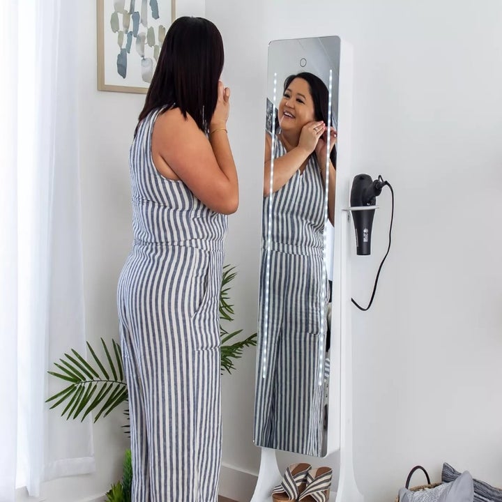 A model looking into the same full length armoire mirror with a blow dryer in the attached slot