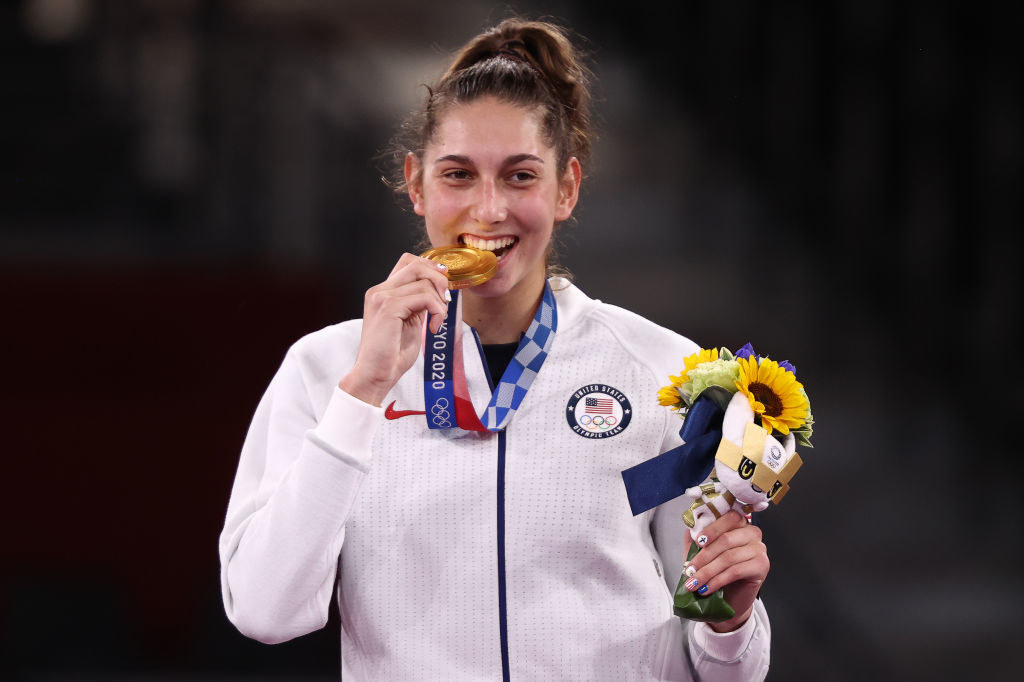 Anastasija Zolotic of the United States bites her medal at the medal ceremony for taekwondo