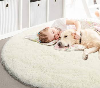 A child and a dog lounging on the white round shag rug