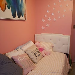 Reviewer's photo showing the white butterfly stickers on a pink bedroom wall