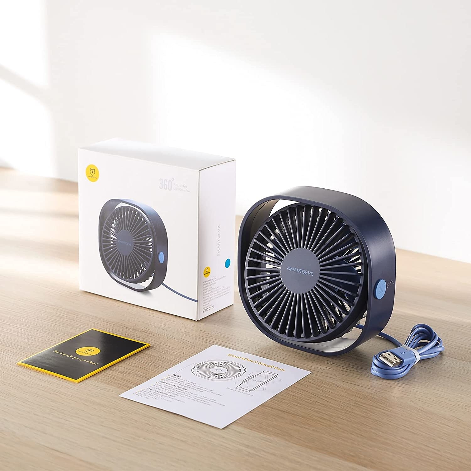 A USB desk fan on the table next to the box and an instruction manual