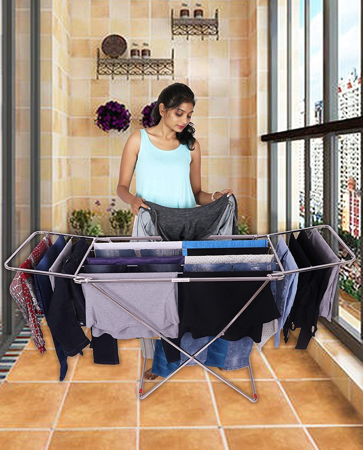 A woman hanging up clothes to dry on the clothing board in the balcony