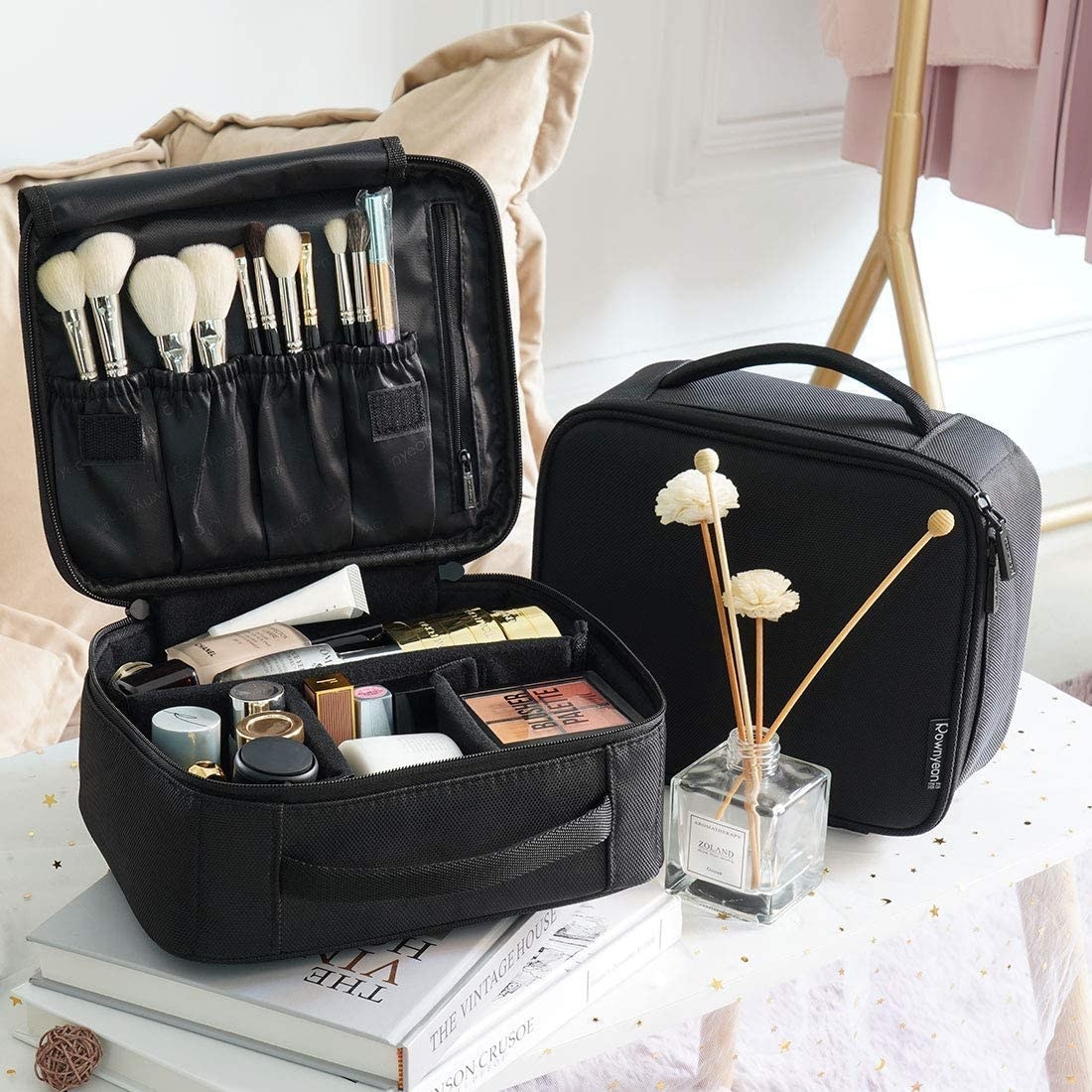 Two makeup cases on a table, one is open and filled with products