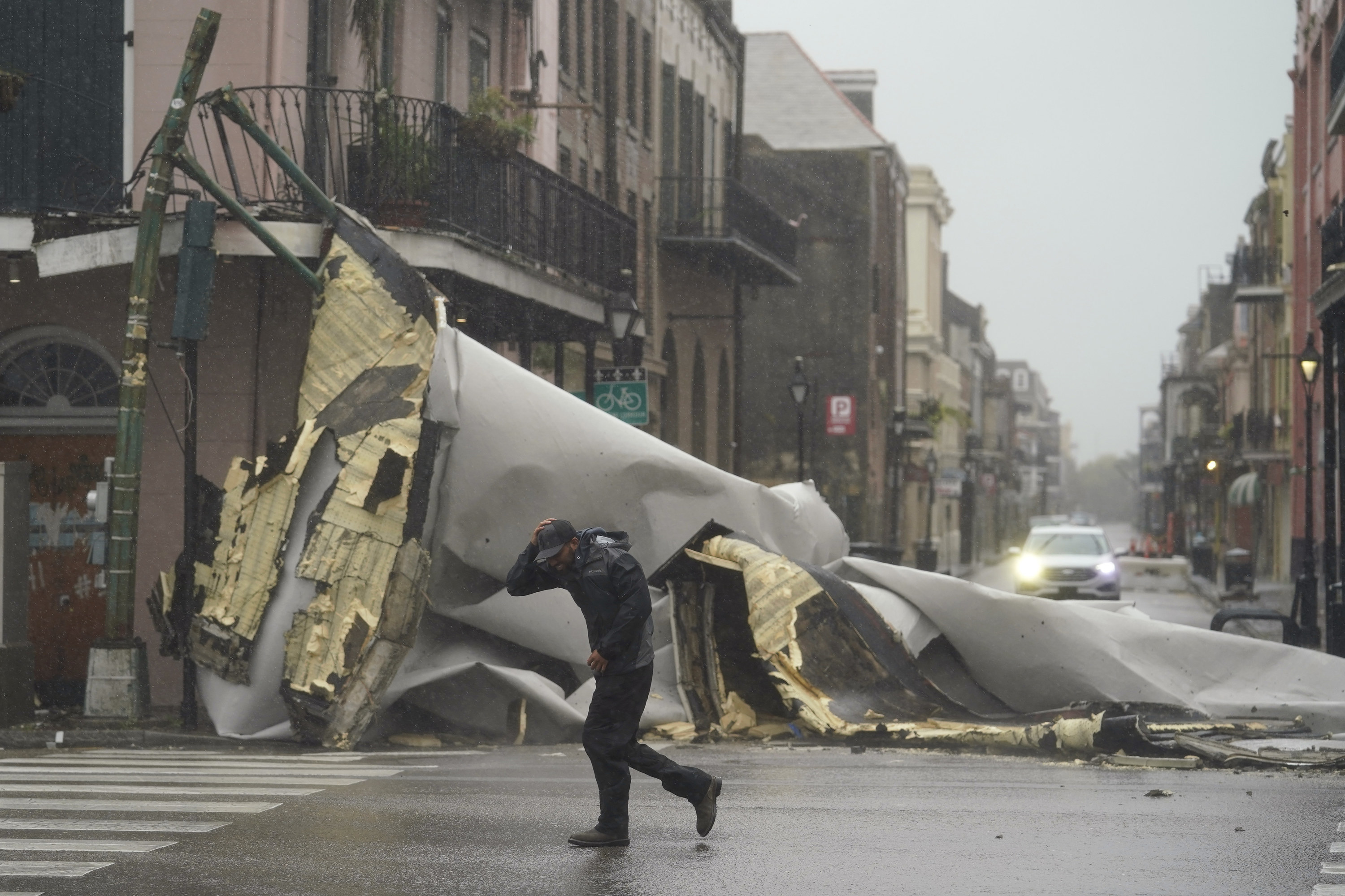 A man passes by a section of roof that was blown off of a building in the French Quarter by Hurricane Ida winds