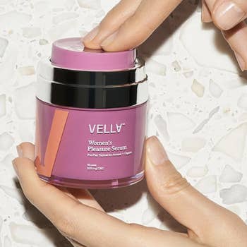 Model pressing top of pink Vella pleasure serum jar