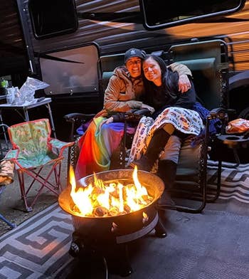 people sit around same propane gas fire pit while camping outdoors 