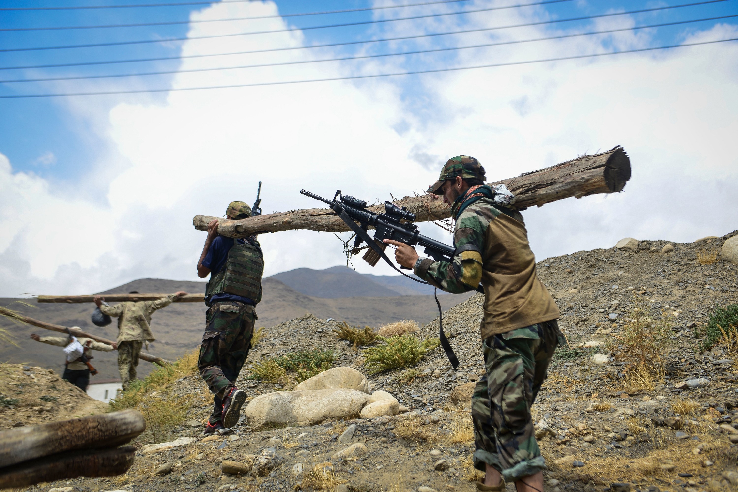 Taliban resistance soldiers hold a log and guns and participate in a training