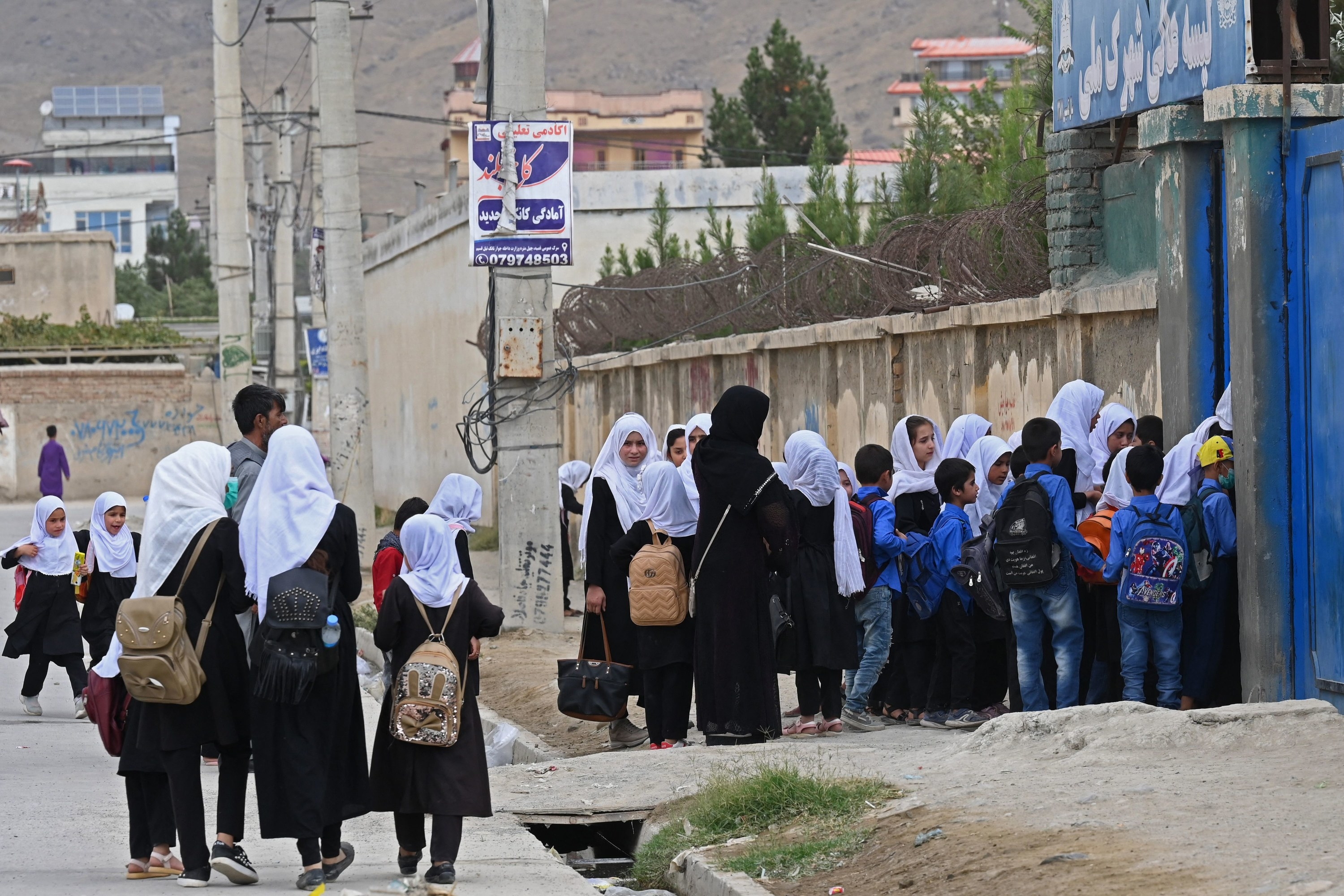 Afghan women and children are seen arriving at a school in the morning