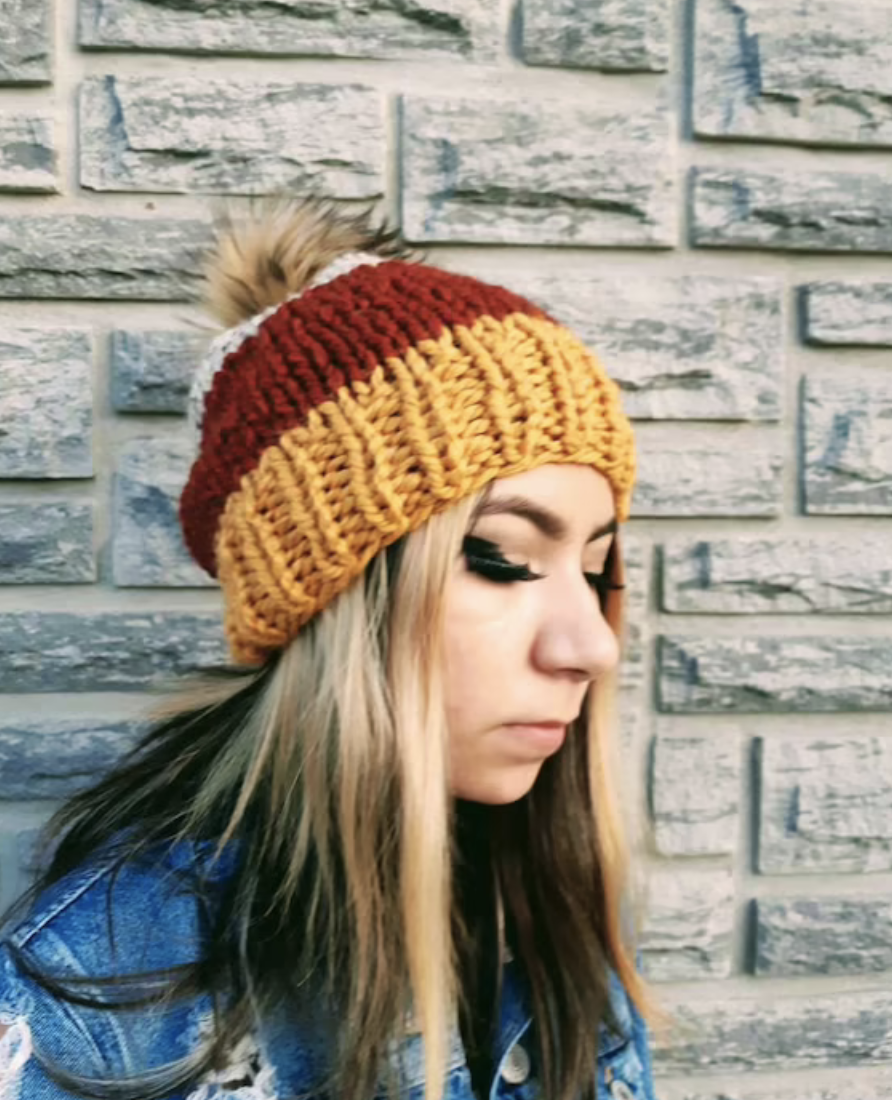 model wears yellow, red, and white candy-corn style beanie with jean jacket