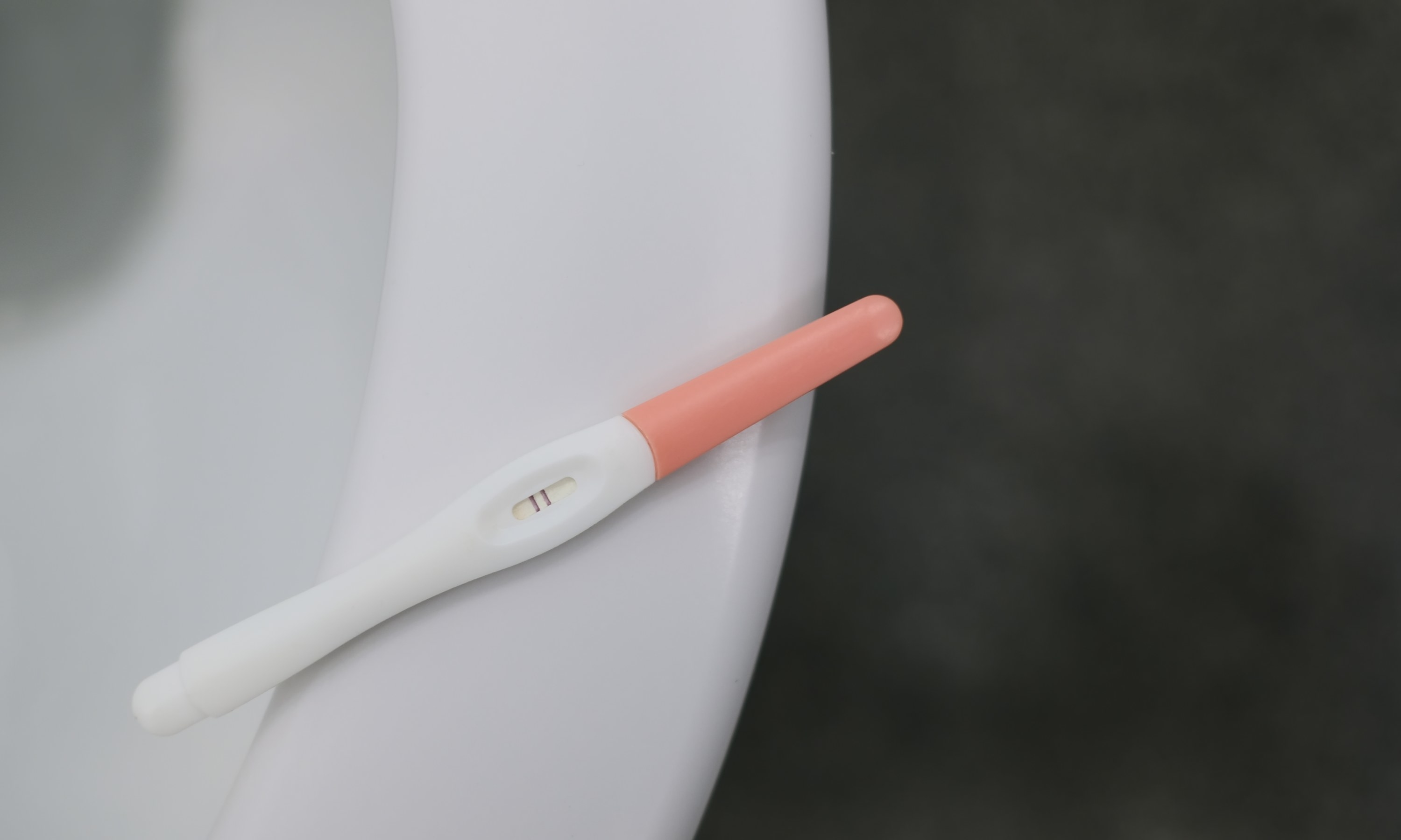 A pregnancy test leaning on a toilet seat