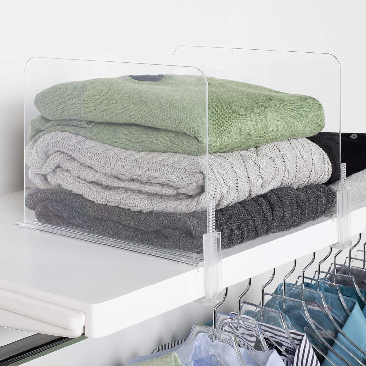 two dividers separate sweaters on a shelf in a closet
