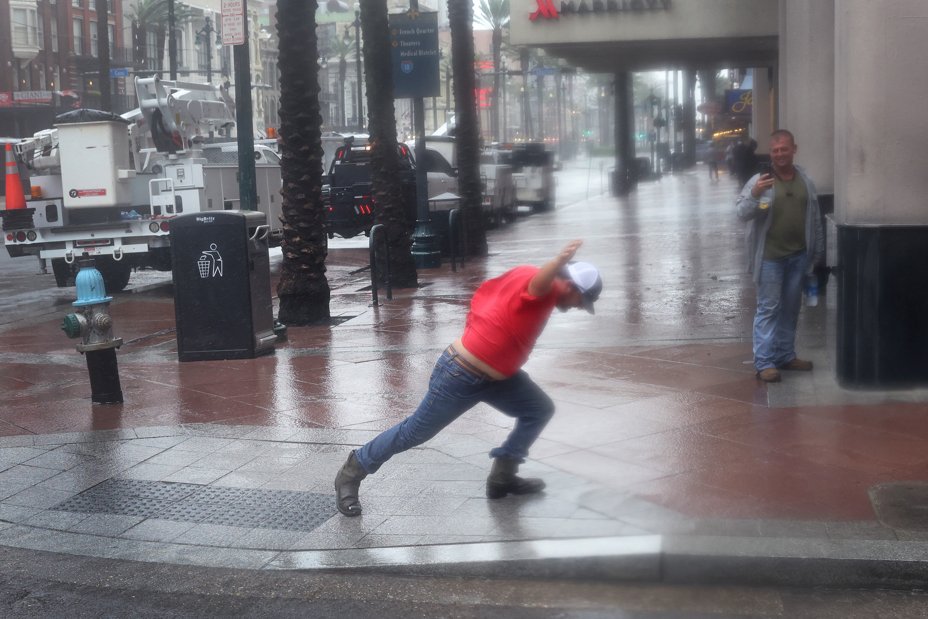 A utility worker walks against the blowing wind