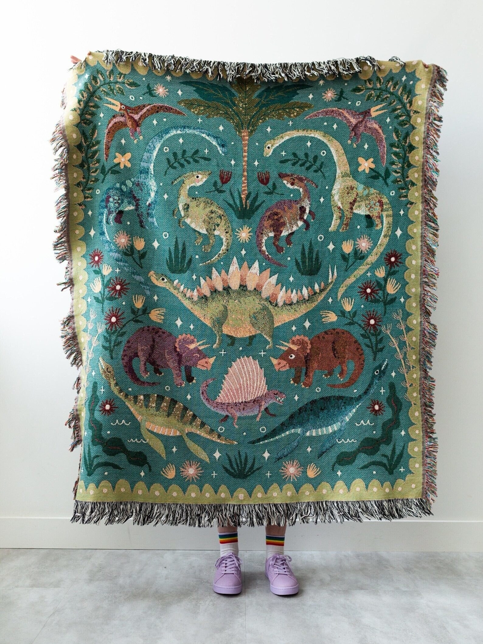 woven tasseled blanket with several different types of dinosaurs on the front
