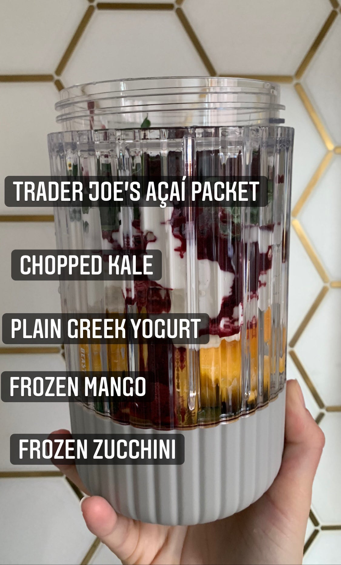 My blending jar with the following ingredients: frozen zucchini and mango, plain greek yogurt, chopped kale, and a Trader Joe's acai packet