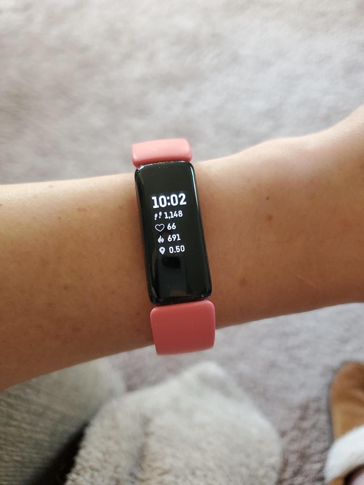 reviewer wears pink Fitbit with daily steps, calories, and heart rate stats on display