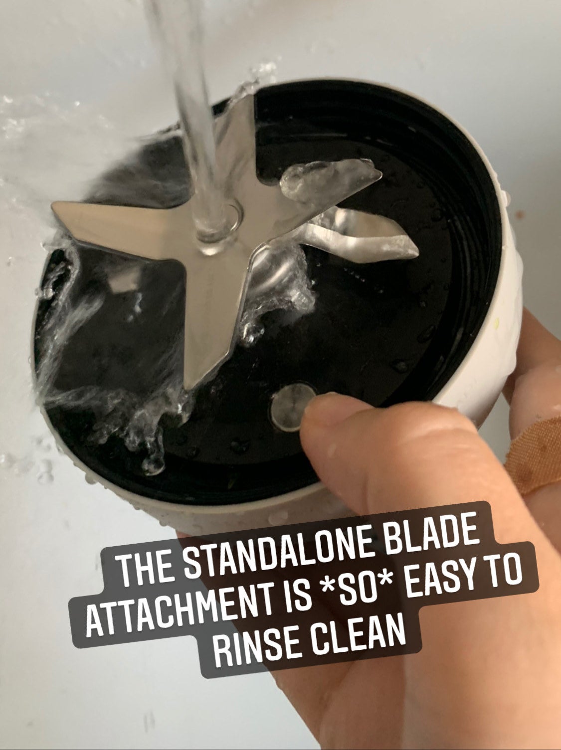 My hand holding the standalone blade attachment under a faucet to rinse clean