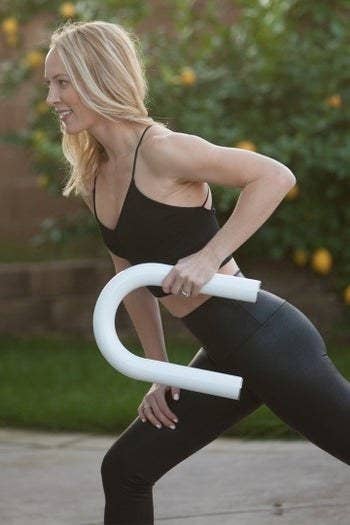 model holds U-shaped white weight while working out outdoors