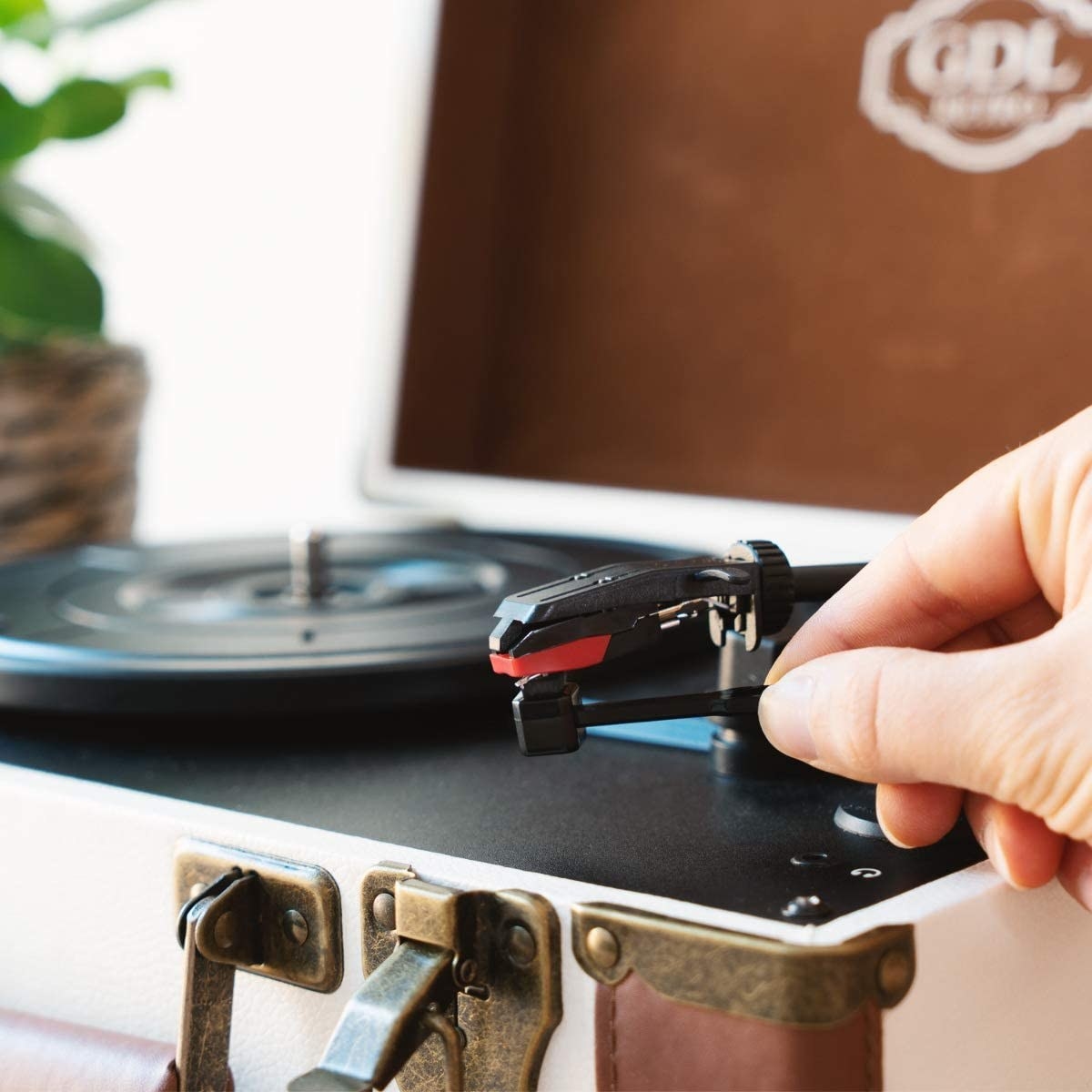 A person cleaning their turntable needle with the tool